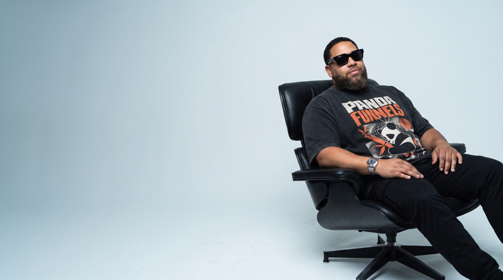 Charles Digital seated in a black chair wearing a Panda Funnels shirt.