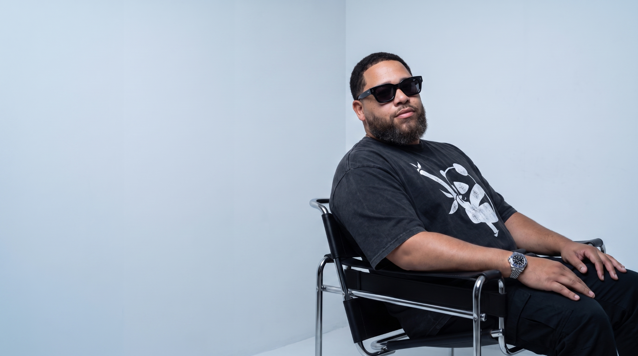 Charles Digital seated in a black chair, wearing a Panda shirt and sunglasses.